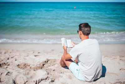 Side view of woman sitting at beach