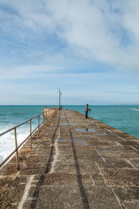Man fishing on sea against sky