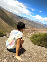Rear view of woman looking at mountains against sky