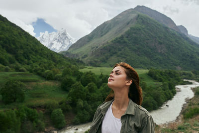 Portrait of young woman standing against mountain