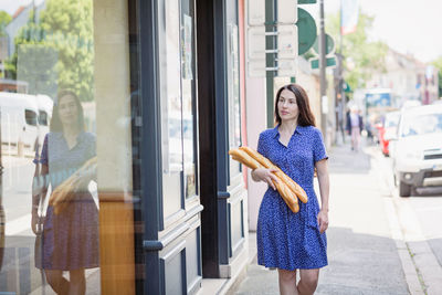 Young woman buying a french baguette