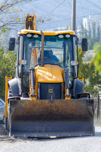 The tractor excavator is yellow on the street. sunny autumn day. crimea, sudak - 10 october 2020.