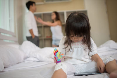 Girl watching video in mobile phone while parents arguing at home