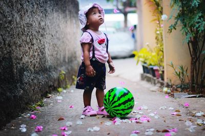 Full length of girl looking away while standing on footpath