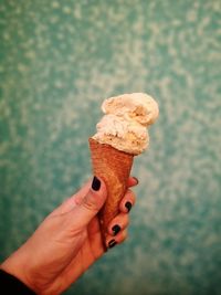 Close-up of hand holding ice cream cone against blurred background