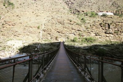 Footbridge over mountain against clear sky