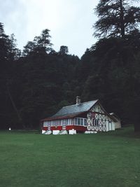 Built structure on field by trees against sky