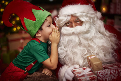 Side view of boy with santa claus sitting at home