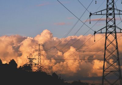 Low angle view of silhouette electricity pylon against sky during sunset