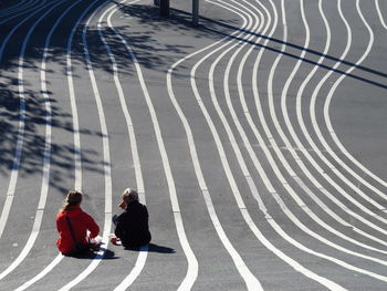 Rear view of siblings sitting on footpath at superkilen park