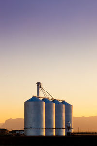 Silo on lands against sky during sunset