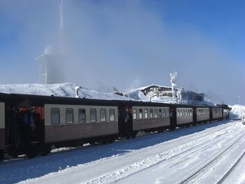 Train on snow covered railroad track against sky