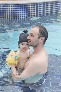 Happy cute asian little girl and her dad spend time together in open air thermal pool.