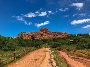 Road leading towards mountain against blue sky