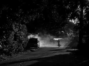 Silhouette person on wet car against sky during rainy season