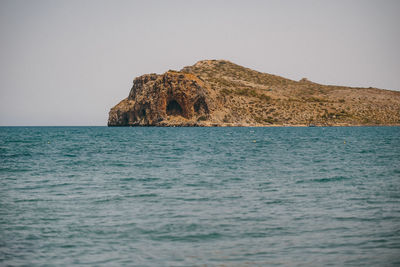 Rock formation in sea against clear sky