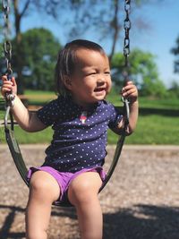 Close-up of cute girl on swing at playground
