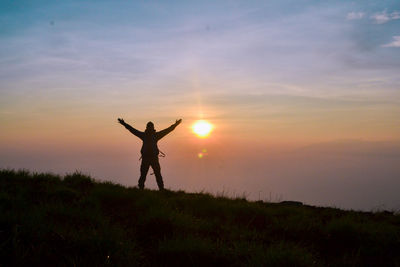 Silhouette person standing on field against sky during sunset