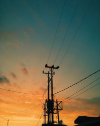 Low angle view of silhouette electricity pylon against dramatic sky