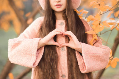 Portrait of kid girl 10-12 year old with long hair wear casual jacket make heart shape with hand