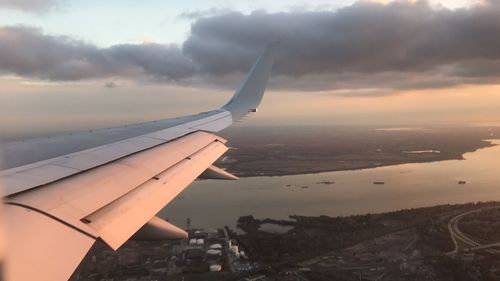 Close-up of airplane wing against cloudy sky