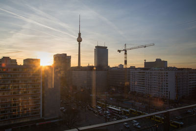 Fernsehturm amidst buildings in city at sunset