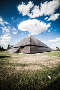 Barn on field by building against sky