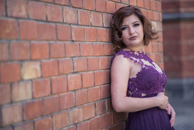 Portrait of woman standing against brick wall