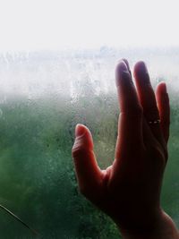 Close-up of hand on wet window