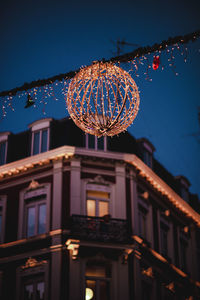 Low angle view of illuminated lighting equipment hanging in city at night