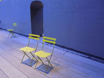 High angle view of yellow chairs on sidewalk against wall