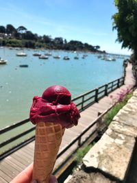 Person holding umbrella by sea against sky