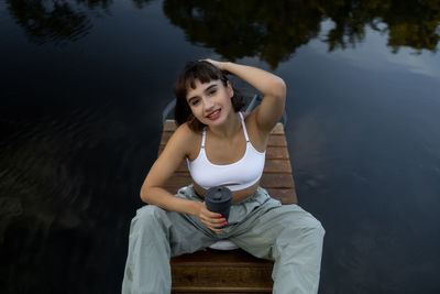 Side view of young woman sitting on retaining wall