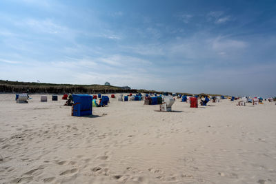 Hooded chairs on beach against sky