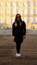 Portrait of young woman standing on road in city