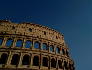 Low angle view of coliseum against clear blue sky