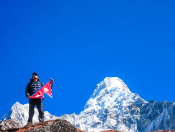 Man standing on snowcapped mountain against clear blue sky