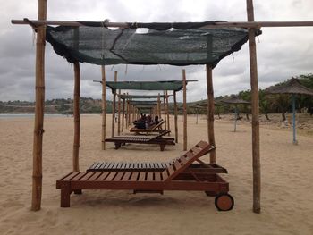 Deck chairs on beach against sky