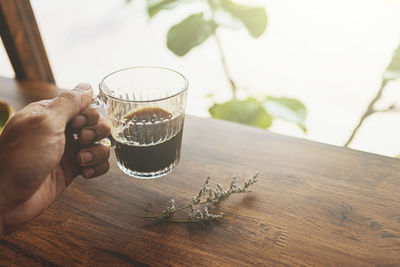 Midsection of person holding drink on table