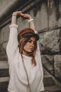 Portrait of young woman with arms raised standing outdoors