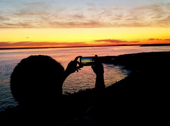 Silhouette of man in sea at sunset