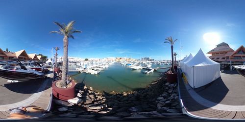 Boats moored at harbor by city against sky