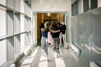 Rear view of two people walking in corridor