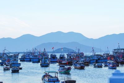 Boats moored at harbor against sky