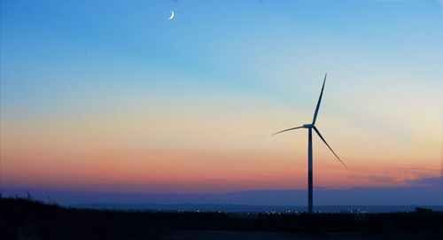 Silhouette windmill on field against sky during sunset