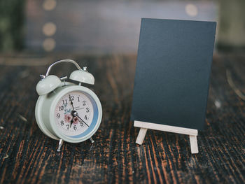 Close-up of clock and blank blackboard on table