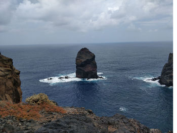 Scenic view of rocks in sea against sky