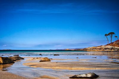 Scenic view of beach against blue sky