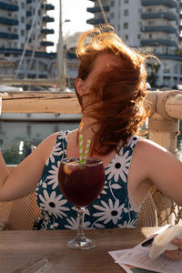 Obscured face of woman with drinking glass on table at cafe