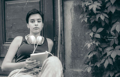 Portrait of young woman sitting on wall